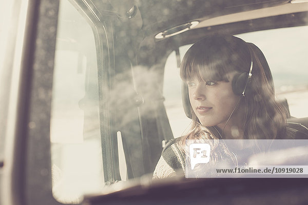 Junge Frau reist im Auto und hört Musik
