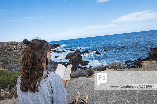 Junge Frau liest Buch am Meer
