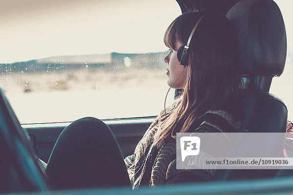Junge Frau reist im Auto und hört Musik
