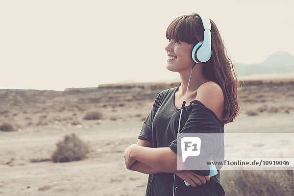 Junge Frau hört Musik und lächelt fröhlich.