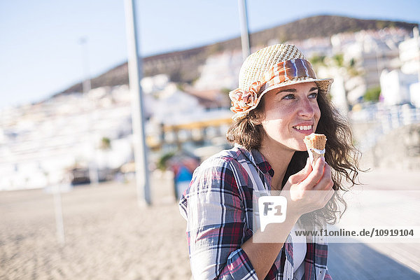 Junge Frau beim Eis essen am Strand