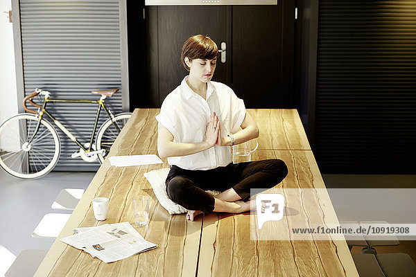 Frau praktiziert Yoga auf Holztisch