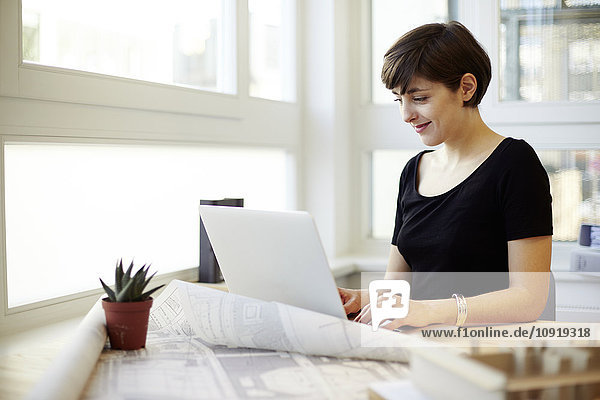 Portrait der jungen Architektin mit Laptop in ihrem Büro