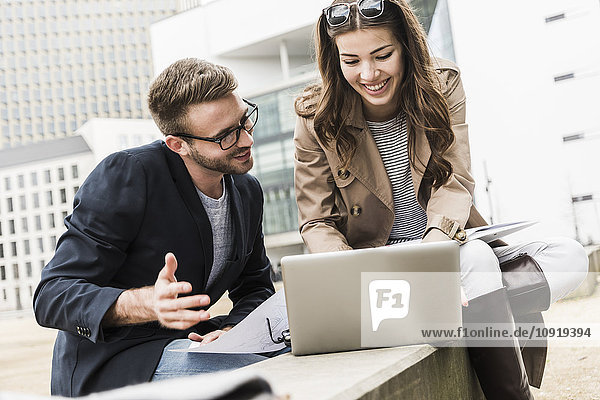 Young business couple working together outdoor  using laptop