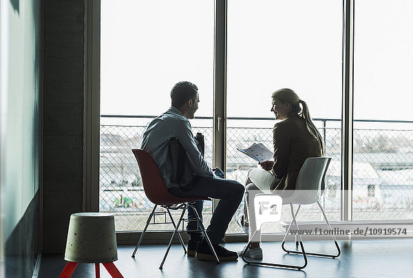 Two colleagues sitting at the window talking