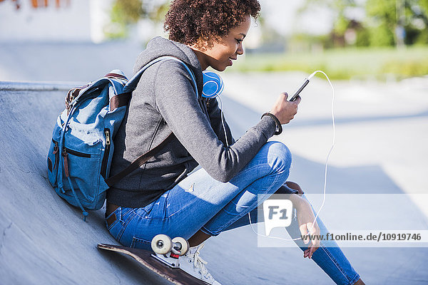 Young woman with headphones  cell phone and skateboard