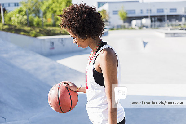 Junge Frau mit Basketball im Skatepark