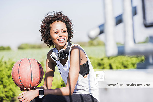 Lächelnde junge Frau hält Basketball
