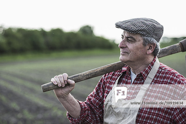 Landwirt hält Werkzeug vor einem Feld