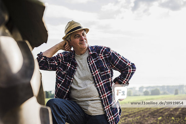Farmer leaning on tractor at a field