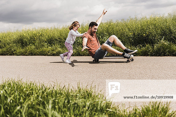 Tochter schiebt Vater auf Skateboard