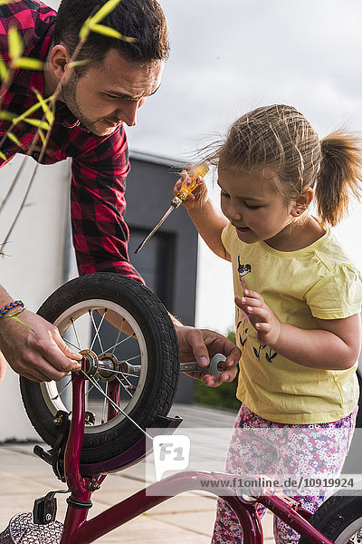 Vater und Tochter reparieren gemeinsam das Fahrrad