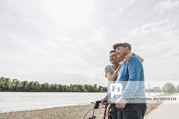 Älterer Mann und seine Tochter stehen am Flussufer.