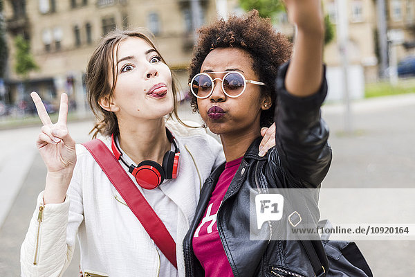 Porträt von zwei besten Freunden  die lustige Gesichter ziehen  während sie Selfie nehmen.