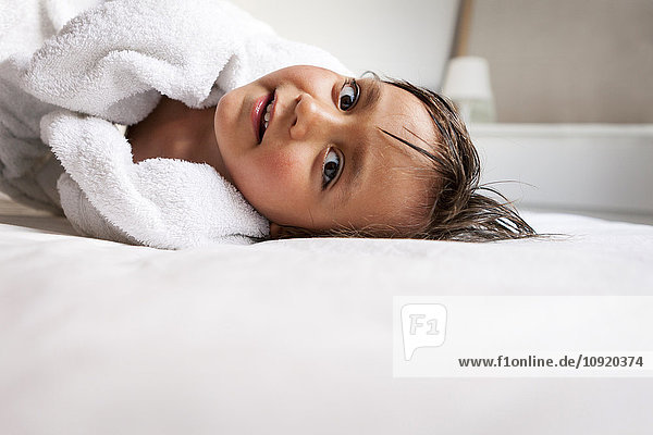 Portrait of little boy with shower towel lying on the bed after taking a bath