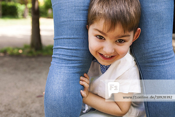 Porträt eines glücklichen Jungen zwischen den Beinen der Mutter