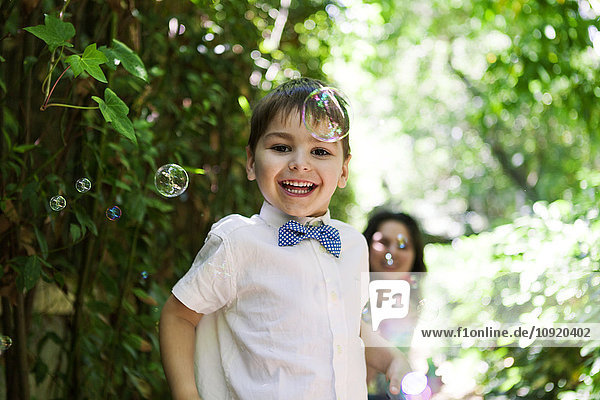 Happy boy with soap bubbles and mother in background