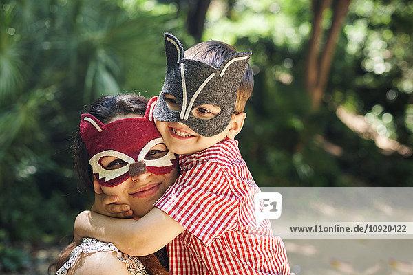 Mutter und kleiner Sohn mit Tiermasken beim Spielen im Park