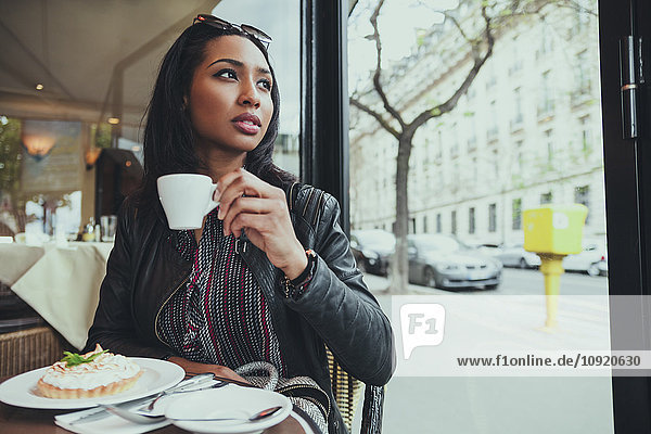 Porträt einer jungen Frau  die in einem Café sitzt und Kaffee trinkt.