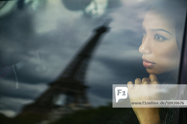Frankreich  Paris  Porträt einer jungen Frau  die den Eiffelturm durch ein Autofenster beobachtet.