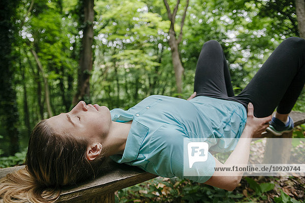 Junge Frau entspannt auf der Bank im Wald