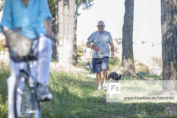 Ein älterer Mann geht mit seinem Hund im Wald spazieren.