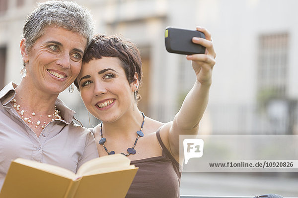 Mother and adult daughter taking selfie with smartphone