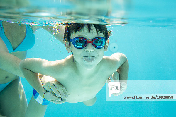 Kleiner Junge taucht  Mutter hilft  Zunge herausstrecken  unter Wasser  Schwimmbad