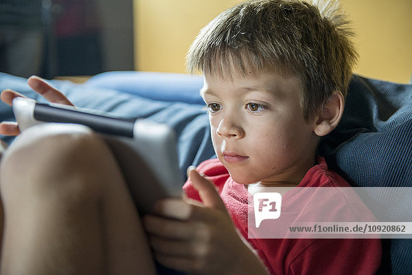 Kleiner Junge mit digitalem Tablett zu Hause