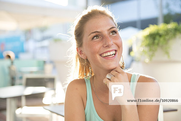 Portrait of happy young woman at outdoor cafe in summer