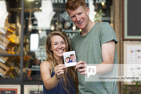 Glückliches Paar  das sich selbst vor einem Coffee-Shop zeigt.