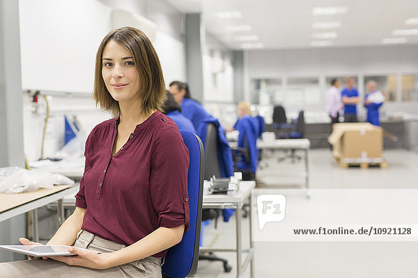 Portrait confident businesswoman with digital tablet in steel factory office