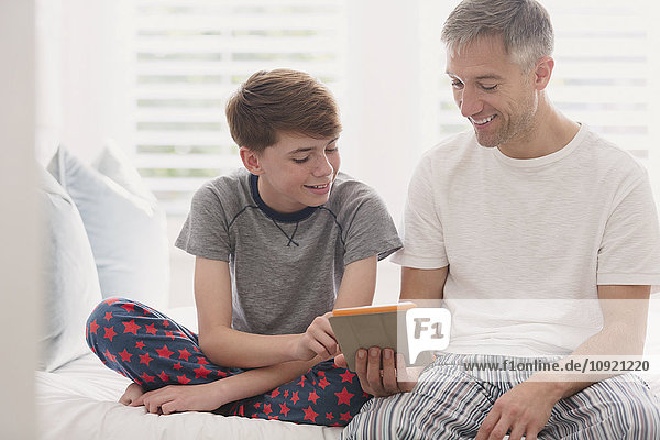 Father and son in pajamas using digital tablet