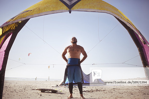 Mann bereitet sich auf Kiteboard am sonnigen Strand vor