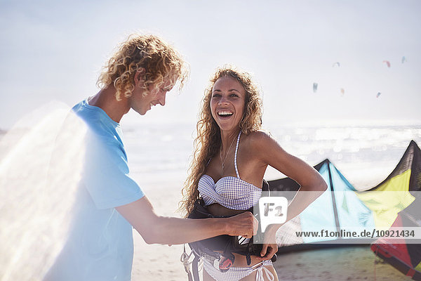 Mann Befestigung Kiteboarding Sicherheitsgurt auf Frau am sonnigen Strand