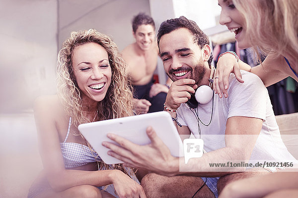 Junge Freunde lachen mit digitalem Tablett