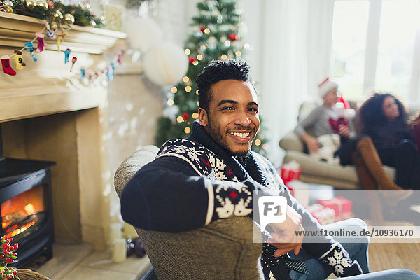 Portrait lächelnder Mann genießt Weihnachten im Wohnzimmer