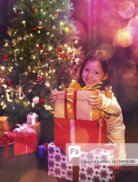 Portrait lächelndes Mädchen mit Stapel Weihnachtsgeschenke