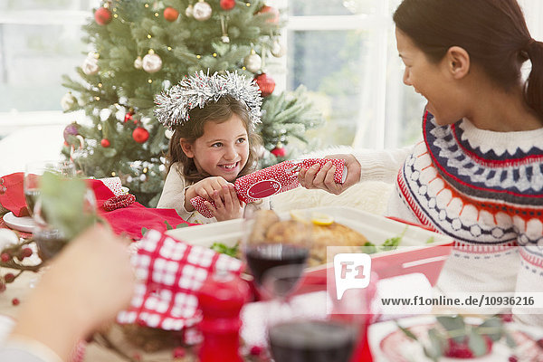 Mutter und Tochter ziehen Weihnachts-Cracker am Esstisch