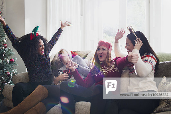 Lachende Freunde feiern Weihnachten auf dem Sofa