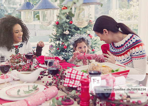 Mother and daughter pulling Christmas cracker at dinner