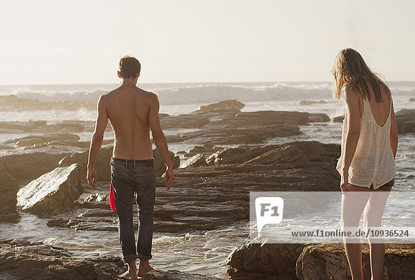Junges Paar spaziert auf Felsen am Meer