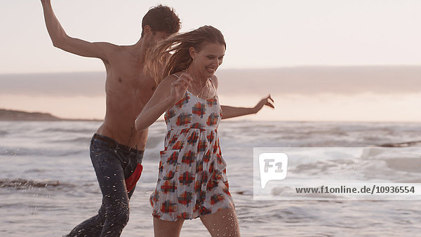 Verspieltes junges Paar läuft am Strand