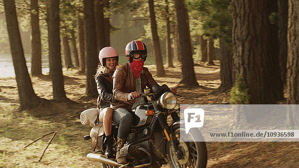 Junges Paar fährt Motorrad im Wald