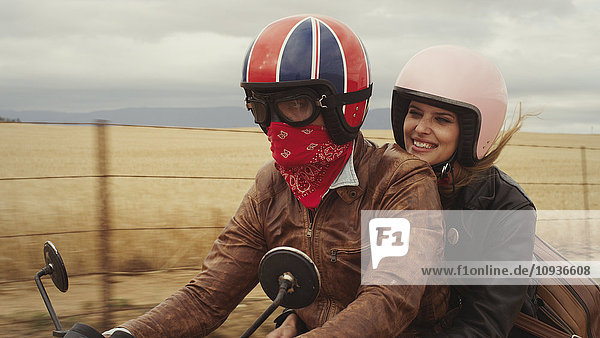 Young couple riding motorcycle in rural countryside