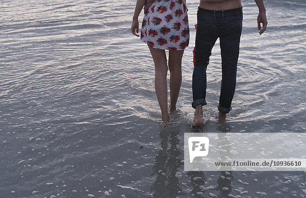 Junges Paar beim Spaziergang in der Meeresbrandung