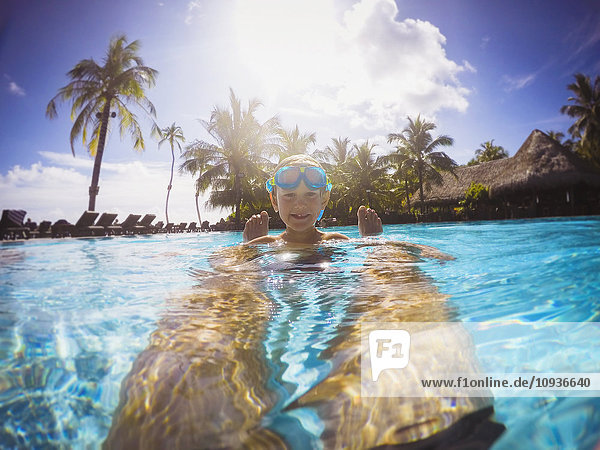 Portrait smiling boy in sunny tropical swimming pool