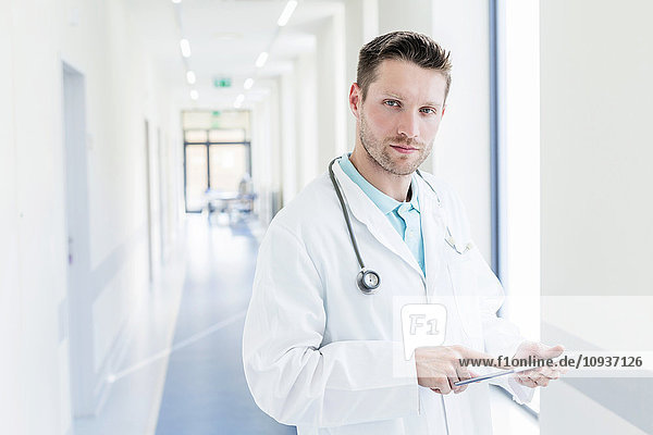 Doctor in hospital corridor using digital tablet