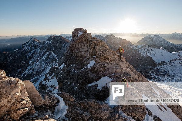 Two mountaineers climbing on mountain peak in European Alps