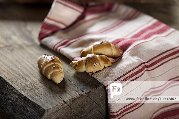 Fresh croissants placed on dish towel on wooden table